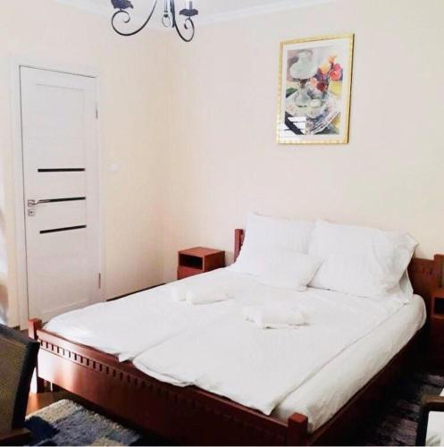 - une chambre dotée d'un lit avec des draps blancs et un lustre dans l'établissement Monica, à Yanoshi