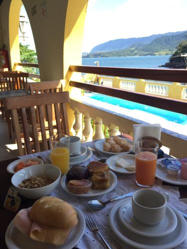 a table with plates of food and drinks on it at Colonial Hotel in Ilhabela