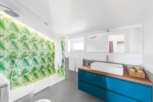 a bathroom with a blue sink and a green leaf wallpaper at Enfasi Holiday Home in Vico Equense