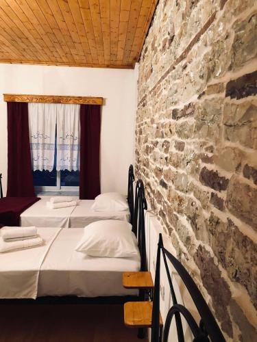 a row of beds in a room with a stone wall at Stone House Obelisk in Gjirokastër