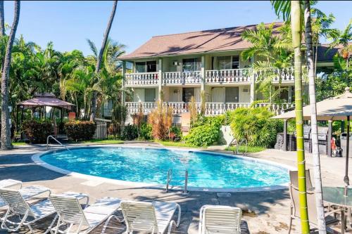 a swimming pool with chairs and a house at Hale Moana, Unit #110 Kona Islander Inn in Kailua-Kona