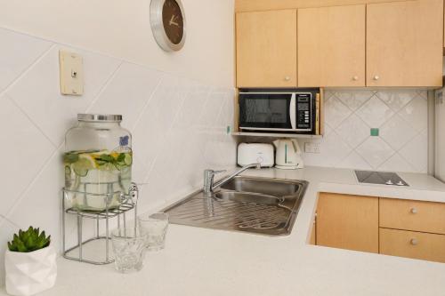 a kitchen counter with a sink and a microwave at Ocean Boulevard in Alexandra Headland