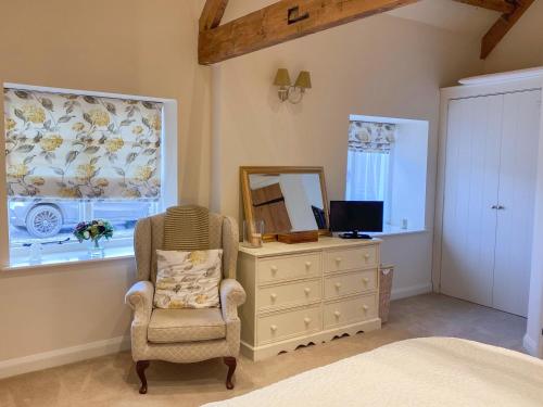 a bedroom with a chair and a dresser and a mirror at The Byre in East Cowton