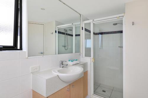 a white bathroom with a sink and a shower at Ocean Boulevard in Alexandra Headland