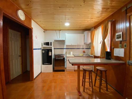 a kitchen with a table and two stools in it at Depto N°1 Temuco Centro in Temuco