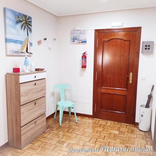 a room with a wooden door and a blue chair at PIEDRAS DE ASTURIAS in Piedras Blancas