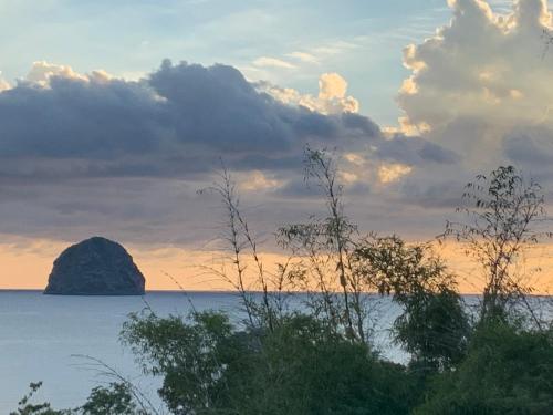 a large rock in the water with a sunset at Ti-CHERRY in Le Diamant