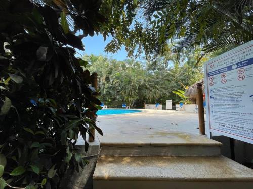 a sign next to a swimming pool next to a tree at The Best of Marbella in Puerto Vallarta