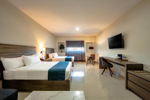 クリアカンにあるInHouse Culiacánのベッドとデスクが備わるホテルルームです。