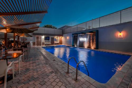 a swimming pool with tables and chairs next to a building at InHouse Hotel Culiacán in Culiacán