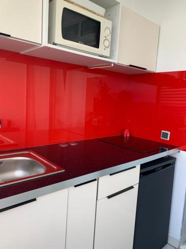 a red kitchen with a sink and a microwave at Ti-CHERRY in Le Diamant