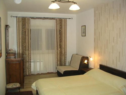 a bedroom with a bed and a chair and a window at Apartment Oliva in Fažana