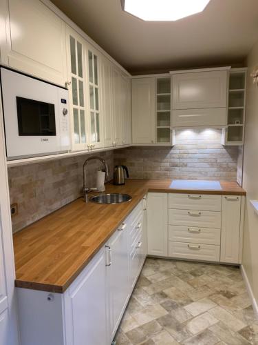 a kitchen with white cabinets and a sink and a microwave at Vaineikio 8 in Palanga