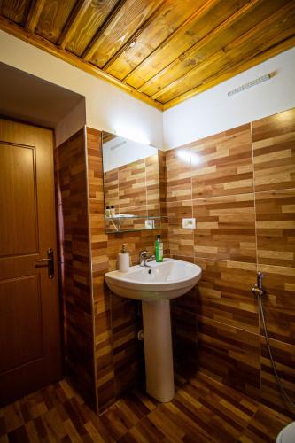 a bathroom with a white sink and wooden walls at Hotel Bebej Tradicional in Gjirokastër