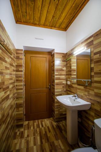a bathroom with a sink and a wooden door at Hotel Bebej Tradicional in Gjirokastër