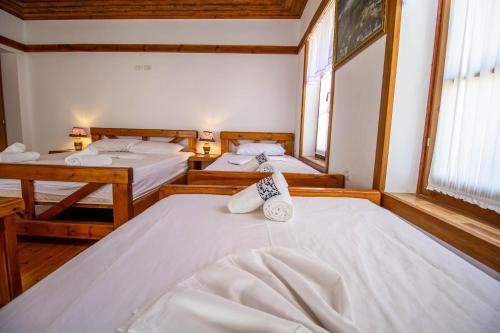 a room with two beds and two windows at Hotel Bebej Tradicional in Gjirokastër