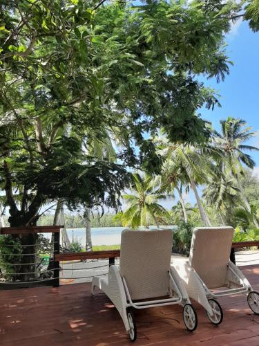 two chairs on a deck with a table and trees at B's Beach House on Muri Lagoon in Rarotonga