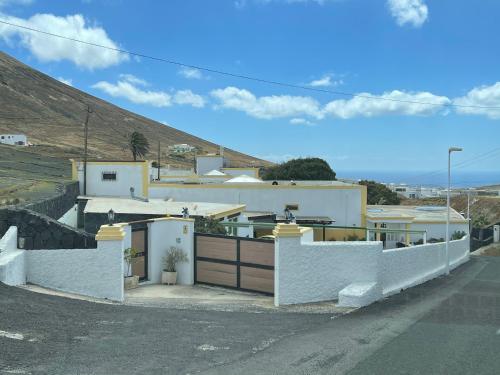 a white house with a gate and a fence at HOTELITO RURAL GA7COLORES only adult in Montaña Blanca