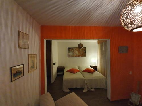 Schlafzimmer mit orangefarbenen Wänden und einem Bett mit orangefarbenen Kissen in der Unterkunft Cuore Alpino in Olivone