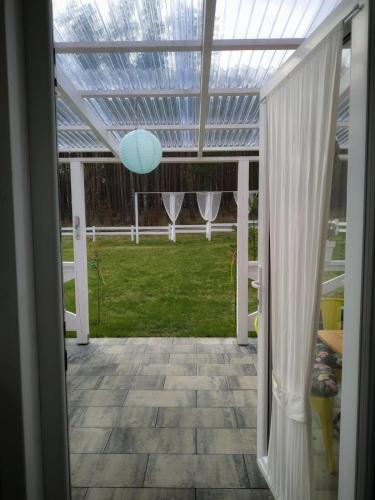 a glass roofed pergola with a view of a yard at Bajkowy domek Villa Rosa na Kaszubach in Grzybowo