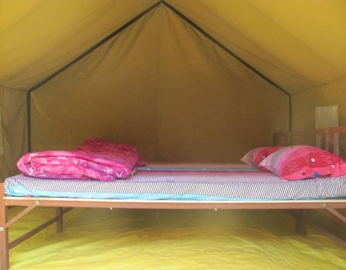 a bed in a tent with two pillows on it at Camping Huts at Lord Shiva Camps in Sari