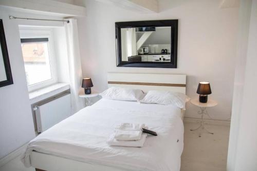 a bedroom with a white bed with a mirror on the wall at Perfect Stay - "Campari Glam Apartments" in Toruń