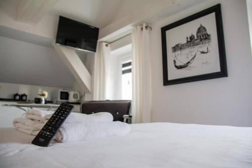 a remote control sitting on top of a bed with towels at Perfect Stay - "Campari Glam Apartments" in Toruń
