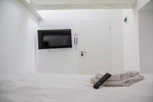 a remote control sitting on a bed in a white room at Perfect Stay - "Campari Glam Apartments" in Toruń