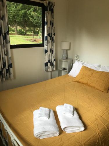 a bedroom with a bed with two towels on it at Tophouse Mountainview Cottages in Saint Arnaud