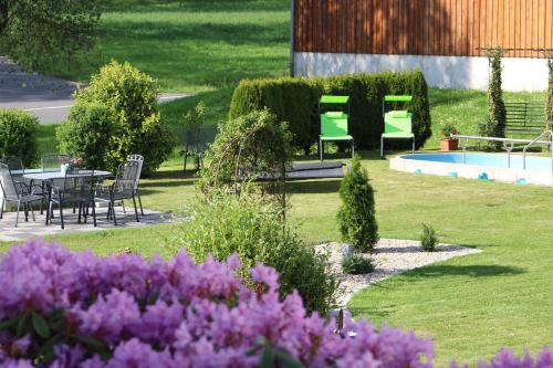 a garden with a table and chairs and purple flowers at Gästehaus Sporrer in Neualbenreuth