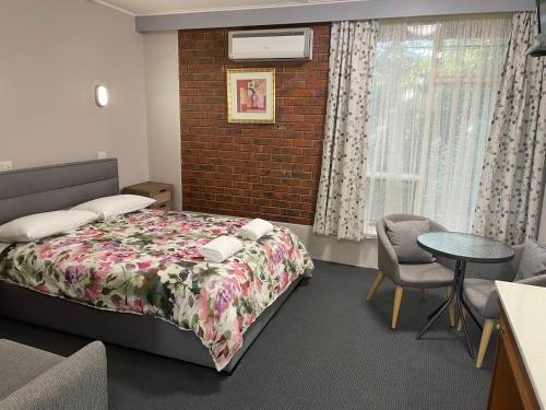 a bedroom with a bed and a brick wall at Camperdown Cascade Motel in Camperdown