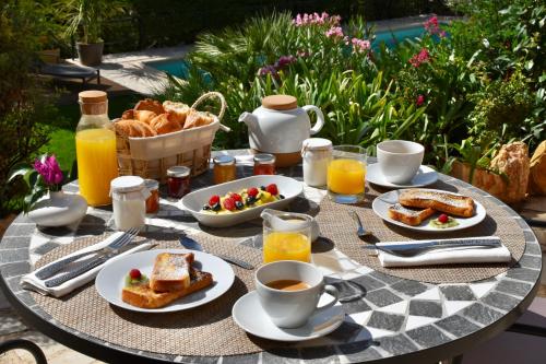 - une table de petit-déjeuner avec du pain grillé, du pain et du jus de fruits dans l'établissement Les Hauts de la Riviera, à Cabris