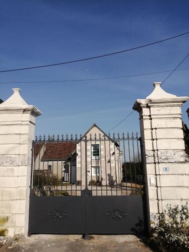 un portail en face d'une maison blanche dans l'établissement Le clos des augers. Chambre Descartes, à Azay-sur-Cher