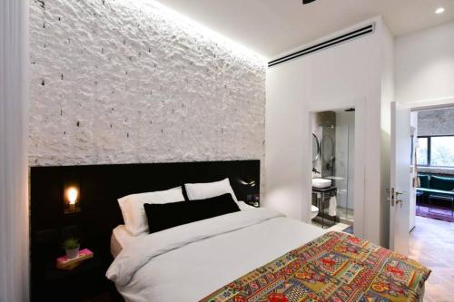 a bedroom with a white bed and a stone wall at Jerusalem of concrete&stell in Jerusalem