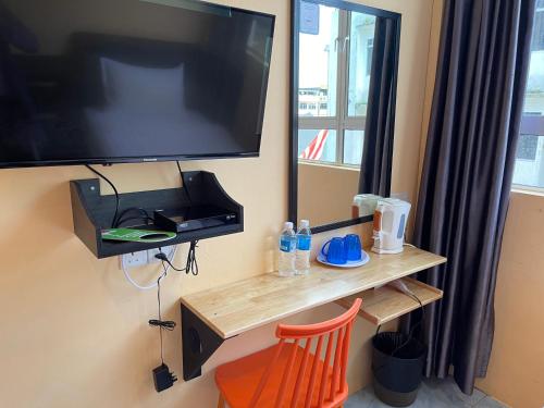uma televisão numa parede com uma mesa de madeira e uma cadeira em Loft Pals Urbanstay Lodge, Kapit em Kapit