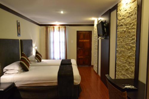 ein Hotelzimmer mit 2 Betten und einem TV in der Unterkunft Citystay West in Maseru