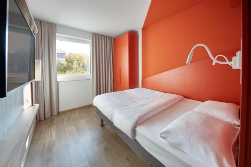 a bedroom with an orange wall and a bed at ibis budget Bayreuth in Bayreuth