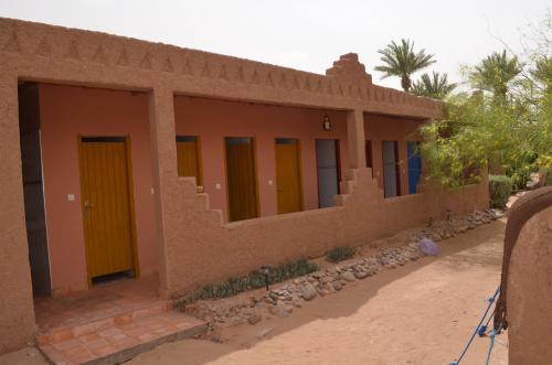 a small house with colorful doors on the side of it at Le Drom'blanc in Mhamid