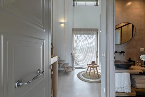 einen Flur mit einem Bad mit einem Waschbecken und einer Badewanne in der Unterkunft Evais Boutique Houses & Luxury Suites in Karystos