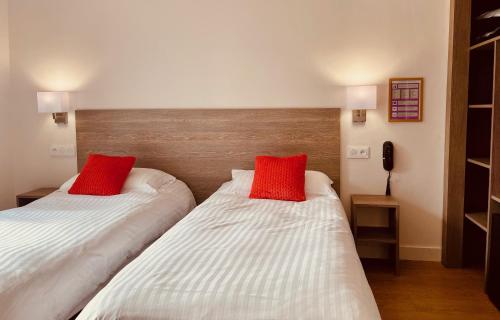two beds in a room with red pillows on them at Hotel Courbet in Juan-les-Pins