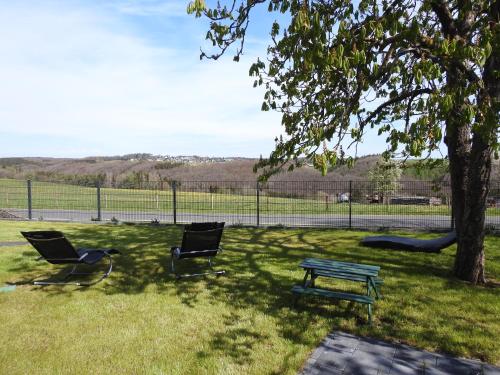 a park with two chairs and a bench and a tree at Ferienwohnungen Eifelausblick in Hümmel