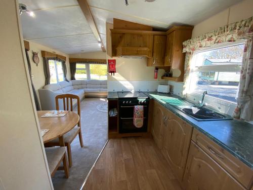 uma cozinha com um lavatório e uma mesa numa caravana em Charming two bedroom static caravan in whithorn em Newton Stewart