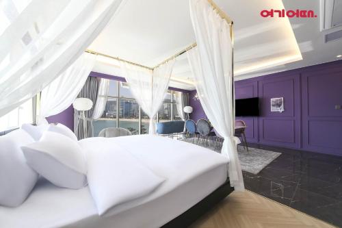 a bedroom with a white bed and purple walls at De Homme Hotel in Busan