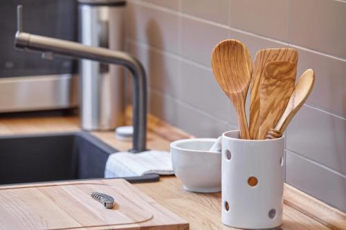 eine Tasse mit Holzgeschirr auf einer Küchentheke in der Unterkunft Düne 6 in Sankt Peter-Ording