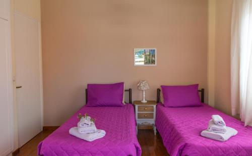 two beds in a room with purple sheets and towels at Spiti Anna Maria in Corfu