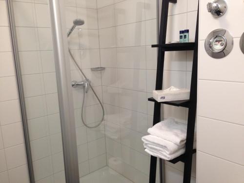 La salle de bains est pourvue d'une douche et de serviettes blanches. dans l'établissement Hotel am Marktplatz, à Gankfoken