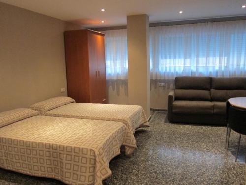 バレンシアにあるApartamentos Abastosのベッド2台とソファが備わるホテルルームです。