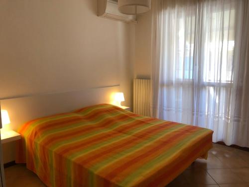 a bedroom with a striped bed and a window at Villa Nadia in Grado