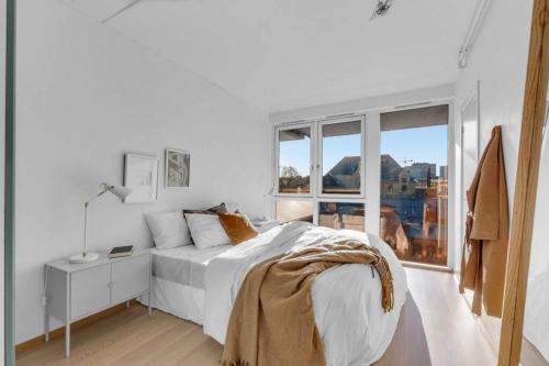 a white bedroom with a bed and a window at Awardwinning penthouse, Oslo city / Grünerløkka in Oslo