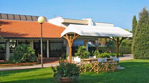 a table and chairs under an umbrella in a yard at Hotel Riva Etrusca in Marina di Bibbona